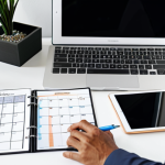 A professional adult, fully clothed in modest business casual attire, diligently planning their online course schedule at a clean, organized desk. The individual is focused on a tablet displaying a detailed digital calendar and a physical planner open to a goal-setting page. The modern home office background features natural lighting and minimalist decor, emphasizing a calm and productive atmosphere. safe for work, appropriate content, perfect anatomy, correct proportions, natural pose, well-formed hands, proper finger count, natural body proportions, professional, high quality.